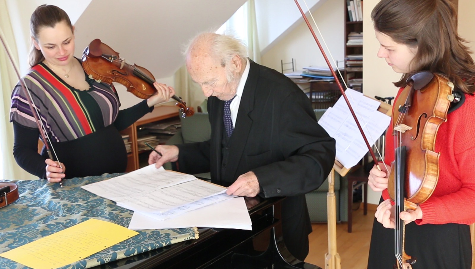 Drei Musiker:innen mit Violinen und Partitur am Klavier